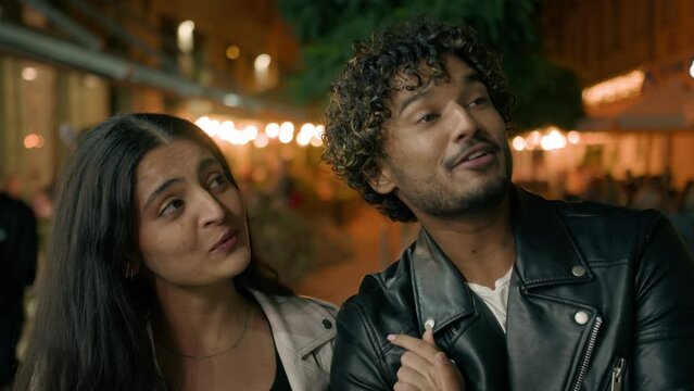 Indian Arabian couple love guy girl woman man friends boyfriend girlfriend walking in night evening city looking at dark light beautiful urban view talking laughing smiling dating contemplate walk