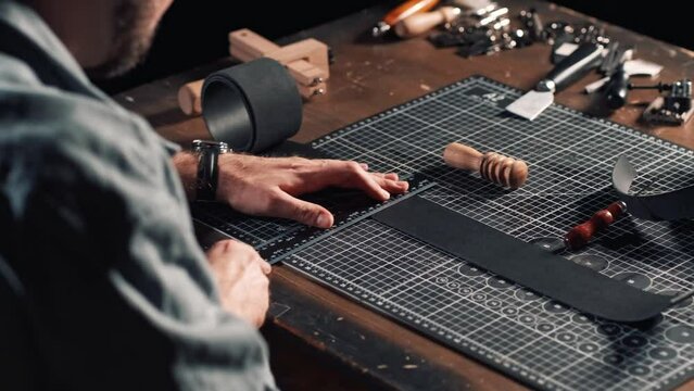 Leatherworker tanner draws, measures with ruler. Tanner works with leather, small business, production.