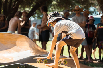 Young boy skating on a long board at a pop up wooden skate ramp.