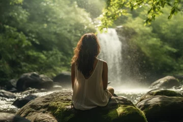 Foto op Plexiglas A young woman wearing casual clothes enjoys a natural waterfall in the forest. woman closes her eyes Feel relaxed and take a deep breath in the fresh air. © เลิศลักษณ์ ทิพชัย
