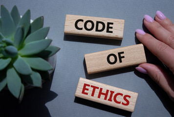 Code of ethics symbol. Concept words Code of ethics on wooden blocks. Beautiful grey background...