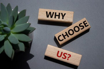 Why choose us symbol. Concept words Why choose us on wooden blocks. Beautiful grey background with...