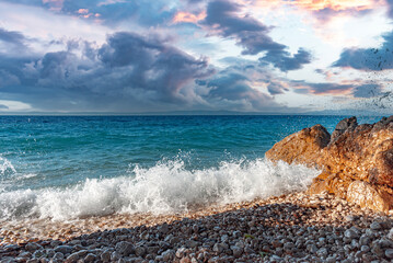 Sea surf. Picturesque seashore with a stone beach at sunset.