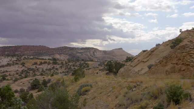 Establishing shot of brown mountains with green forest in The Hogback Scenic Root 12, Utah, North America. Day time on October 2023. ProRes 422 HQ.