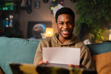 Smiley African American dark skinned musician writing new lyrics sheet music and composing his next...