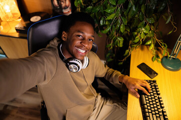 Happy handsome african american dark skinned guy gamer, playing an online game with friends and...