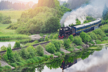 Retro steam train moves along the lake.