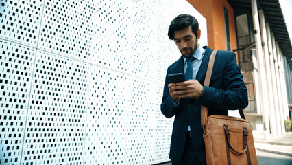 Smart manager looking at mobile phone and walking at street while wearing suit. Skilled investor looking mobile phone to checking sales or working while holding coffee cup. White background. Exultant. - obrazy, fototapety, plakaty