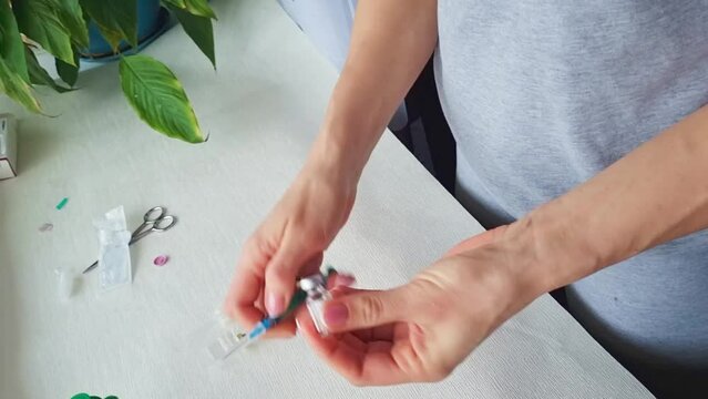 Close up footage of the woman with beautiful hands, preparing hormone medicine and injecting herself to the abdomen with pierced bellybutton. Family planning