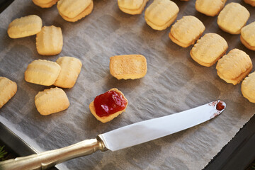 Spreading red marmalade on homemade Christmas cookies