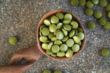Green barley grass tablet on a wooden spoon, top view