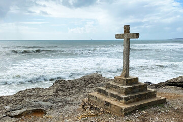 Stone cross on the coast of the Atlantic ocean in Tarragona, Spain