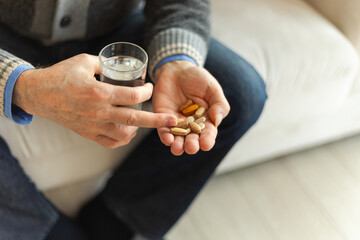 Hands with pills. Senior man hands holding medical pill and glass of water. Mature old senior grandfather taking medication cure pills vitamin. Age prescription medicine healthcare therapy concept - obrazy, fototapety, plakaty