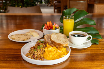 Colombian breakfast with arepas, coffee, bread, eggs, warmed rice and fruit