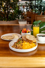 Colombian breakfast with arepas, coffee, bread, eggs, warmed rice and fruit