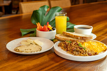 Colombian breakfast with arepas, coffee, bread, eggs, warmed rice and fruit