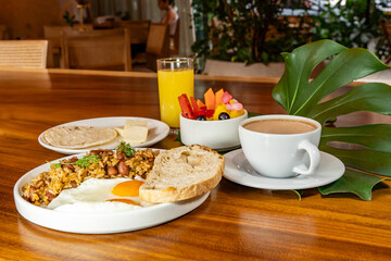 Colombian breakfast with arepas, coffee, bread, eggs, warmed rice and fruit