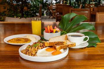 Colombian breakfast with arepas, coffee, bread, eggs, warmed rice and fruit