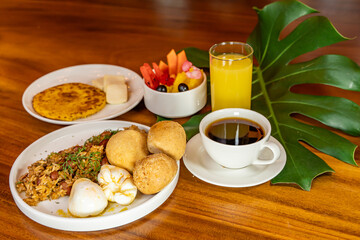 Colombian breakfast with arepas, coffee, bread, eggs, warmed rice and fruit