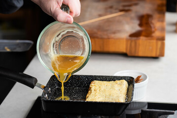 Chef man hands cooking Tamagoyaki or Tamago traditional Japanese Rolled Omelette recipe, made by...