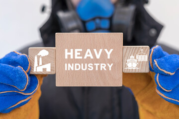 Engineer or industry worker holding wooden blocks with icons sees inscription: HEAVY INDUSTRY....