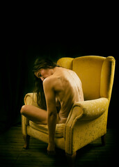 woman sitting showing her naked back in a yellow armchair II