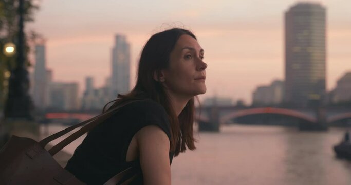 Aesthetic portrait of young beautiful romantic woman with the river view during beautiful pink sunset in London