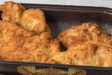 Fried chicken cutlets in a triple wrap on a pan.