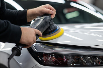 Process of polishing white car hood surface using orbital polishing machine. 