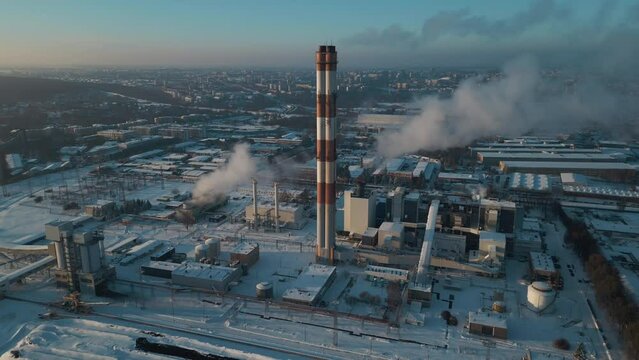 industrial aerial top view of heating power station and chimney or smoke stack at snowy weather, cold winter and snow 4k