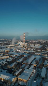 industrial aerial top view of heating power station with chimney or smoke stack at snowy teather, cold winter and snow