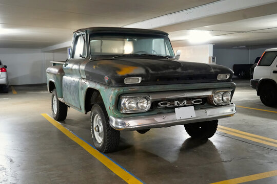 Honolulu, HI - December 13, 2023：Classic 1960's GMC V6 General Motors tuck Company 1966 C-series green pickup truck with rust in parking garage.