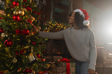 Merry Christmas. African American woman decorating Christmas tree. Happy girl near traditional Christmas tree with classical red golden decorations ornament. Christmas eve at home time for celebration