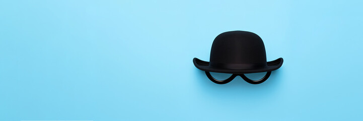 Classic black bowler hat on blue background, simulates face of vintage silent film characters, associated with gentlemanly attire.Vintage Style and Fashion. Movember Men's Health - obrazy, fototapety, plakaty