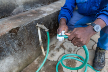 First shot of the hands of an African plumber cutting a pipe