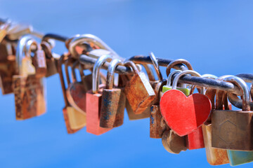 Close up of old rusty love locks on chain against background of blue sea on sunny day. Trip for...