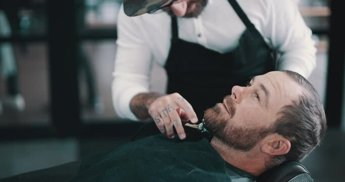 Relax, beard or shave with a barber and man in a seat as a customer for luxury or professional service. Industry, salon or hairdresser and a person grooming the face of a client with a machine