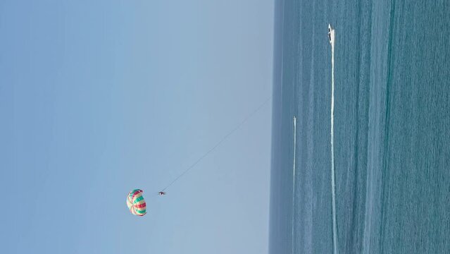 The coast of Thailand on a sunny day, beach entertainment - parachute behind a motorboat, people parachute over the sea