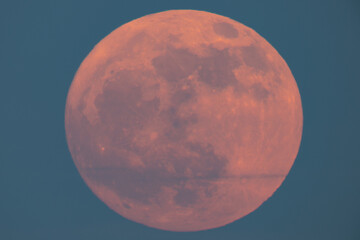 Super strawberry moon rising over the sea, a reddish full moon rising over the sea on a summer...