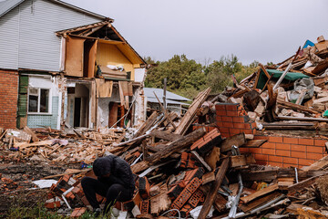 Sad man on ruined house. Hopeless, homelessness, result of military conflicts and natural disasters...