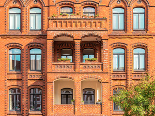 Facade of typical residential red bricks building with arched windows. Apartment house in Hannover,...