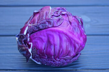 one purple fresh head of purple cabbage lies on a black wooden table