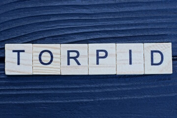 text the word torpid from brown wooden small letters on a black table