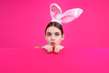Beautiful young woman with bunny ears and Easter eggs on studio background. Festive bunny and easter eggs season. Stylish woman in Easter bunny ears isolated on studio background.