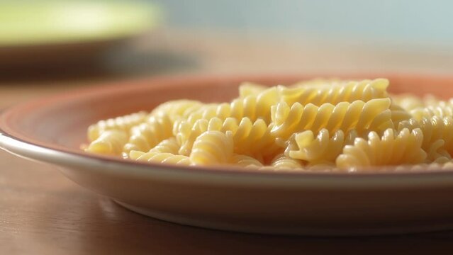 Cooked Fusilli Pasta on Terracotta Plate. Close-up, shallow dof.