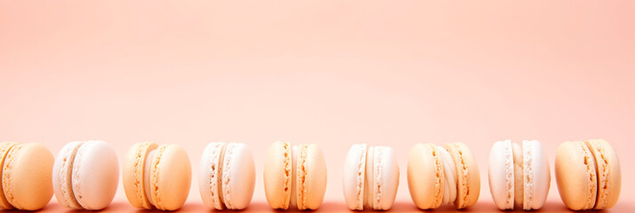 A row of macarons sitting on top of a table. Monochrome peach fuzz background.