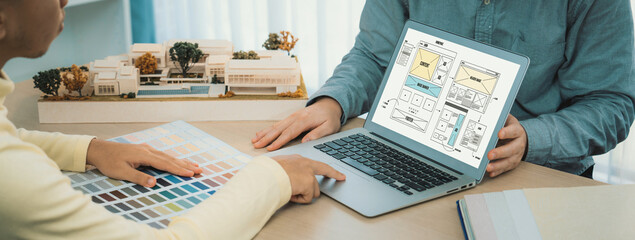 Cropped image of interior designer presents color from color swatches while laptop displayed website wireframe designs for mobiles app and website. Creative design and business concept. Variegated.