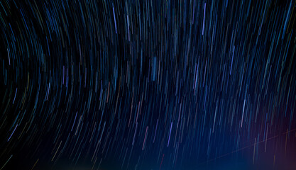 Abstract photo of Blue Night sky star trail background.Startrails on a dark blue sky at night,center sky area.Rotating star lines - obrazy, fototapety, plakaty