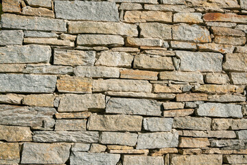 texture of a stone wall with rugged and wrinkled surface, characterized by a variety of earthy tones and intriguing details, offering an atmosphere of authenticity and solidity.