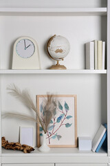 White shelves with books, globe and different decor indoors. Interior design